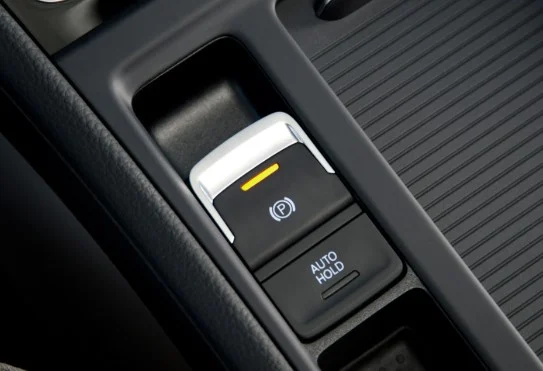 Close-up of a car’s electronic parking brake and auto hold buttons, with the parking brake indicator lit in orange—perfect for navigating Kimberly Idaho’s fastest-growing streets or managing your transmission on busy roads.
