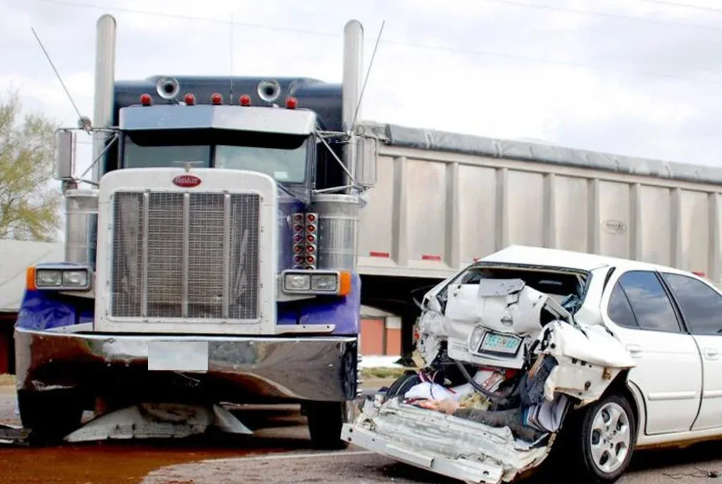 A large semi-truck and a white car involved in a crash in Littleton, Colorado; the car’s rear is badly damaged, and debris is visible around the scene—possibly raising concerns about the importance of regular brake inspection and brake service.