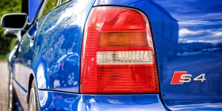 Close-up of the rear left side of a blue Audi S4 car, showing the tail light and S4 badge, with reflections visible on the car’s surface—an ideal visual reminder of how important regular vehicle maintenance and brake system service at Grease Monkey Pocatello can be in keeping your ride both safe and stylish.