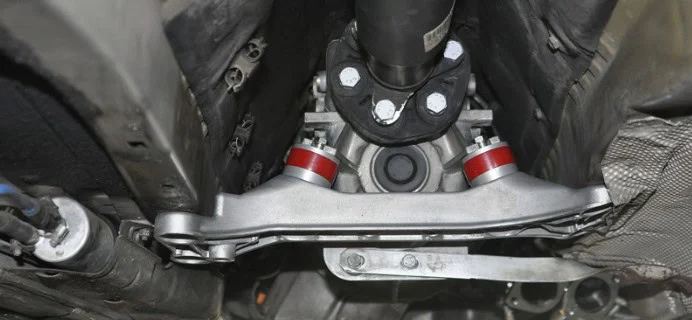 Close-up view of a car’s drivetrain and suspension components, including a driveshaft, bolts, and metallic arms, seen from underneath the vehicle—an essential vantage point for identifying transmission problems or early transmission warning signs in your Laramie.