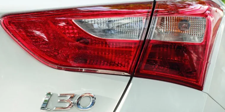 Close-up of the rear taillight and the “i30” badge on a white car.