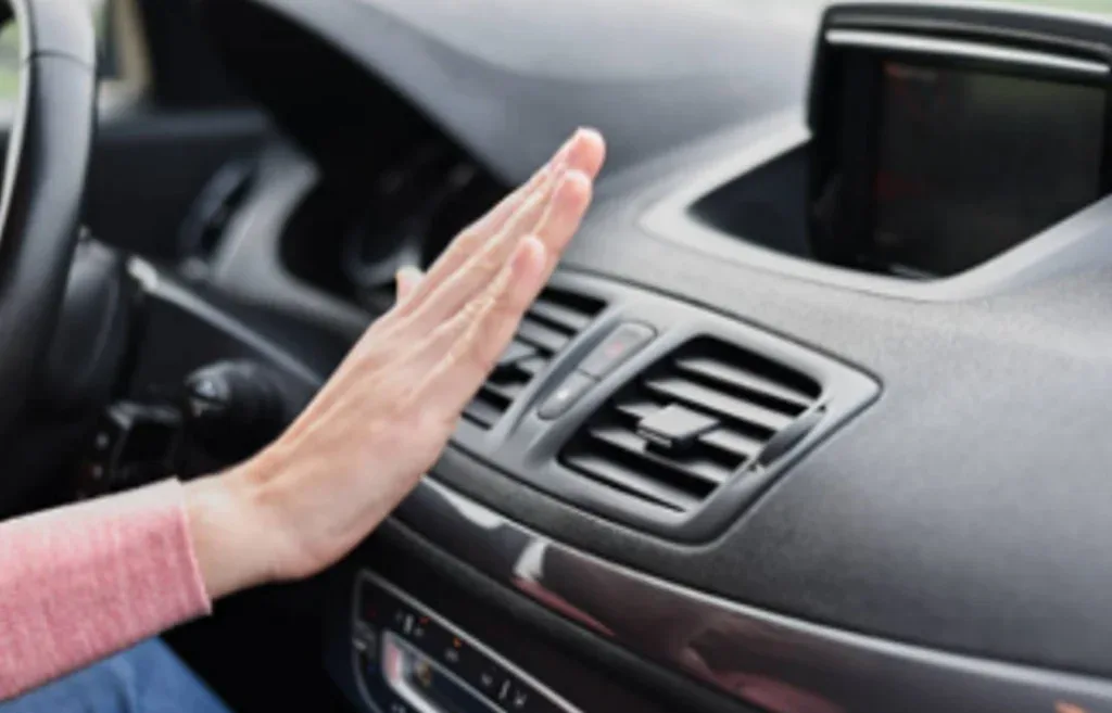 Person holds hand in front of car air vent, checking airflow from the dashboard in a modern vehicle interior—perhaps while driving along Highway 30 near Pocatello West Side, or making sure the cabin air filter is working efficiently.