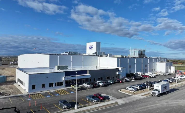 Large white industrial building in Jerome, Idaho, with multiple parked cars and a delivery truck in front, under a partly cloudy sky—an ideal location for car maintenance services such as replacing your cabin air filter.