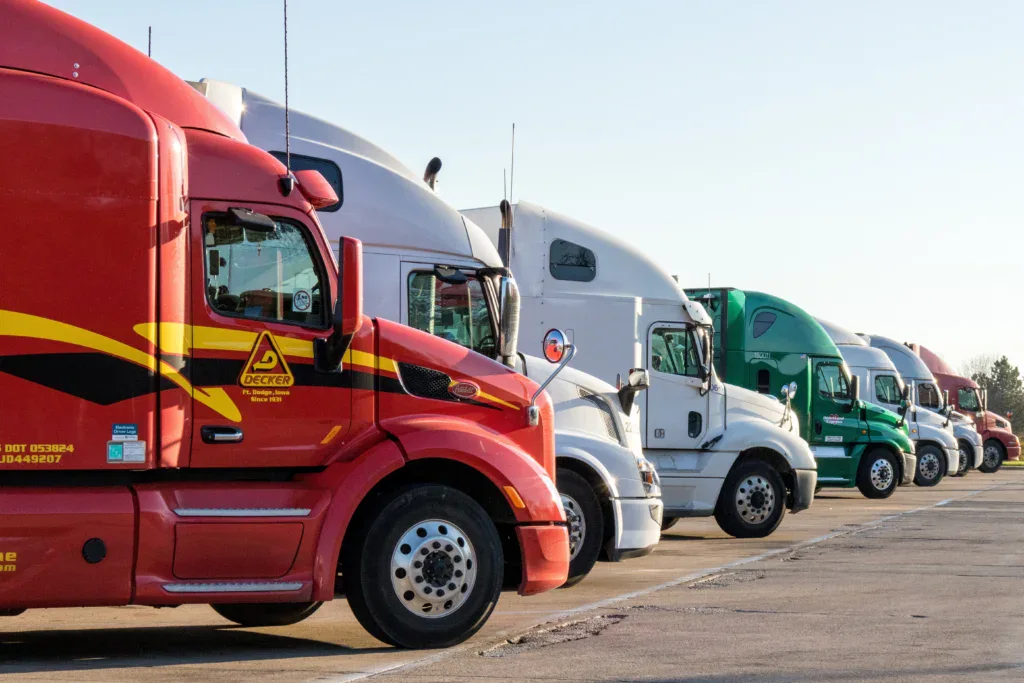 A red Decker semi-truck parked in a line during Pocatello truck maintenance, with other trucks nearby.
