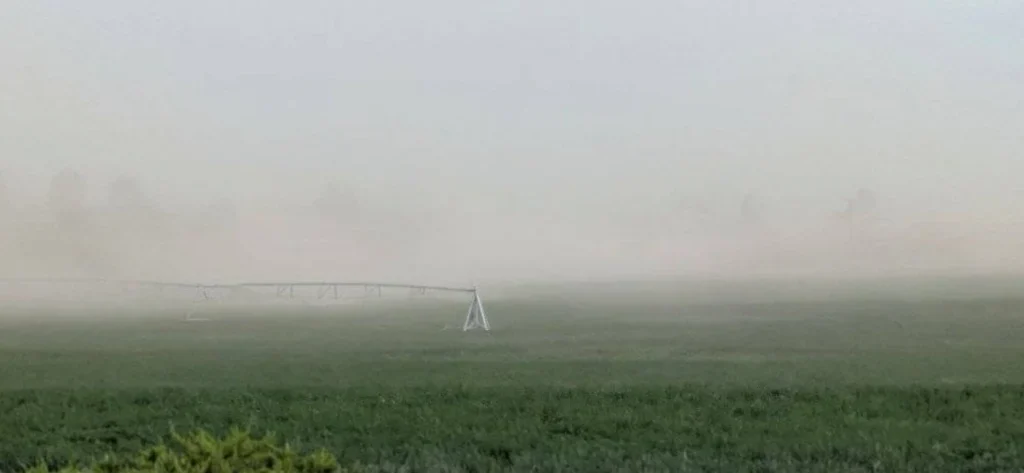 An irrigation pivot system in a field obscured by Jerome wind and thick dust.