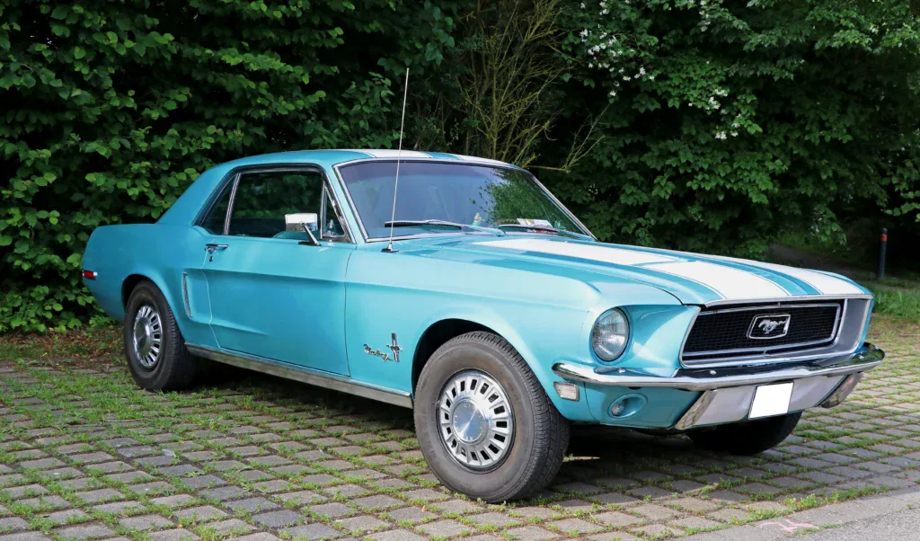 A light blue classic Ford Mustang coupe with white racing stripes parked on a paved lot, a prime example for Rexburg car maintenance.
