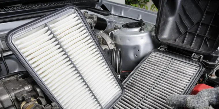 A clean rectangular car engine air filter held next to a dirty, used filter during engine air filter maintenance in Aurora.