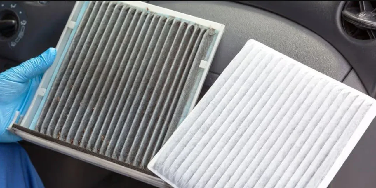 A hand in a blue glove holds a dirty, used cabin air filter next to a clean replacement, essential for Laramie car maintenance.
