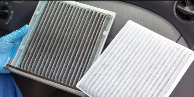 A hand in a blue glove holds a dirty, used cabin air filter next to a clean replacement, essential for Laramie car maintenance.