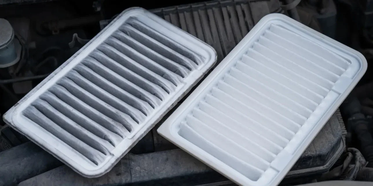 A dirty, used engine air filter from Elizabeth Ranch next to a clean, new replacement filter.