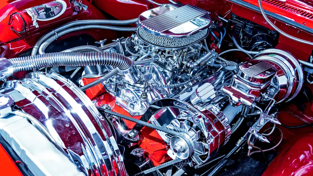 A detailed view of a polished chrome car engine with a bright red engine bay, typical of professional truck maintenance.